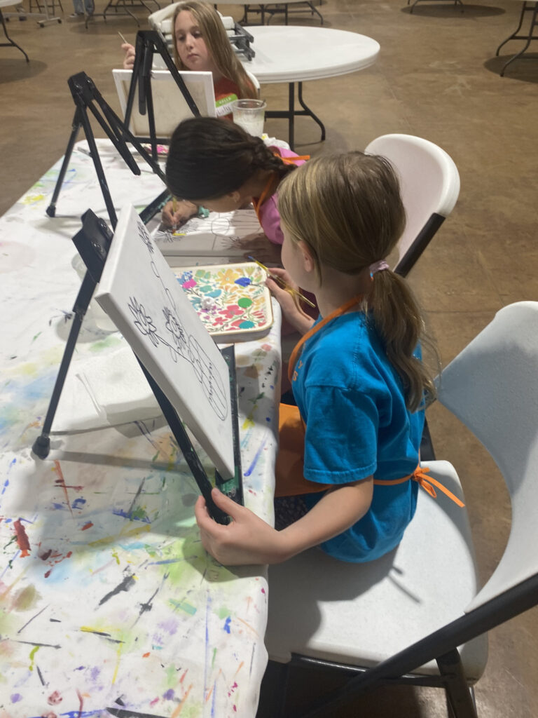 Children painting on canvases at an art class.